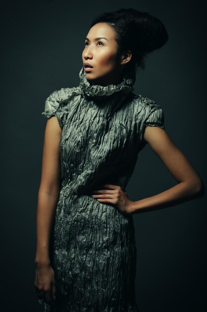 Beauty and fashion concept young Asian fashion model in grey dress against black background