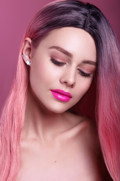 Beauty fashion model with colorful dyed pink hair Girl with bright makeup and pink lips Woman with pink long hair