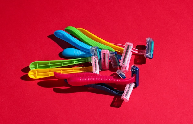 Beauty and fashion pop art concept. Many colored plastic razors on red.