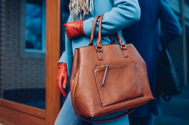 Photo beauty and fashion. stylish fashionable woman wearing coat and gloves ,holding brown bag handbag