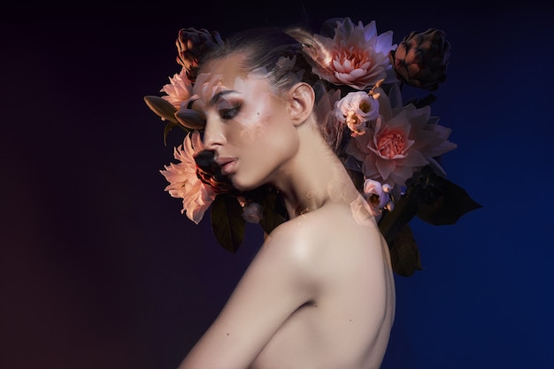 Beauty flowers face of a woman with double exposure. Portrait of a girl neon light and color, professional makeup, nude back of a woman, flowers in the head