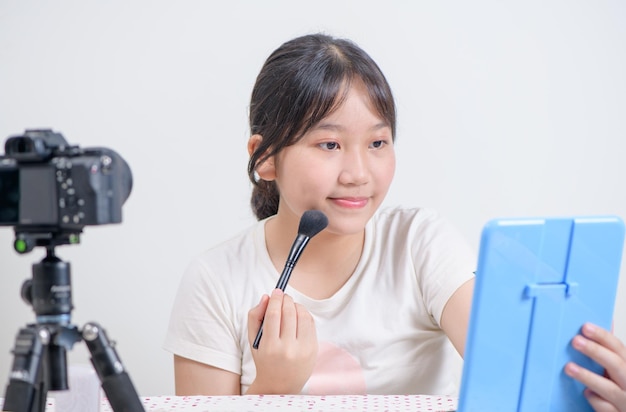 Foto beauty girl blogger concept donna asiatica usa pennello di trucco e recensione in live streaming isolata su sfondo bianco