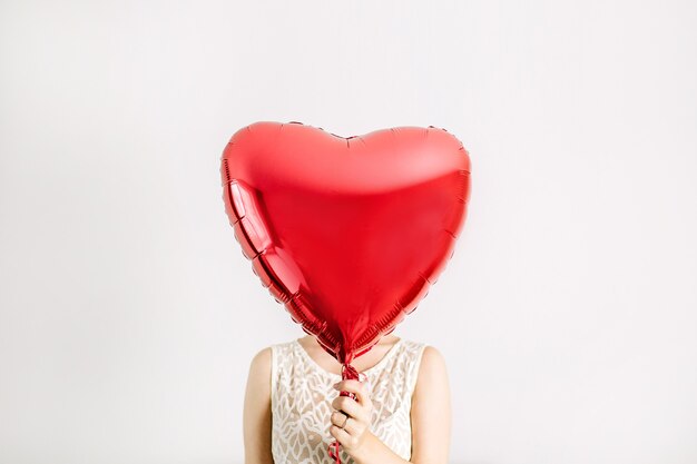 Ragazza di bellezza che tiene il pallone rosso di forma del cuore. concetto di amore