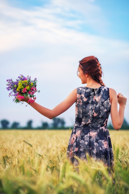 Beauty Girl Outdoors enjoying nature. Beautiful Teenage Model girl in dress on the Spring Field