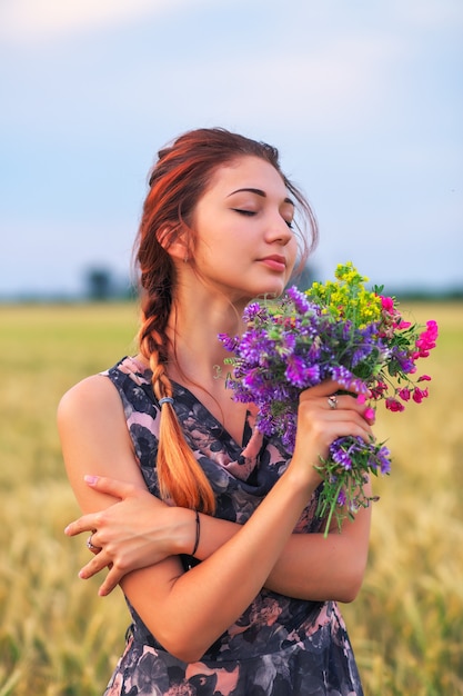 Beauty Girl Outdoors enjoying nature. Beautiful Teenage Model girl in dress on the Spring Field