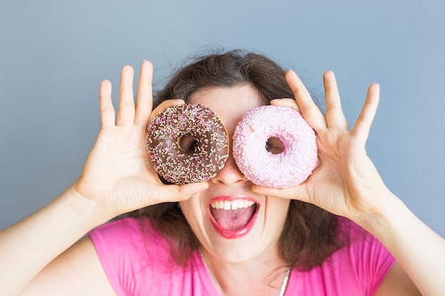 Ragazza di bellezza che prende ciambelle colorate. donna gioiosa divertente con dolci, dessert. dieta, concetto di dieta. cibo spazzatura, celebrazione e festa.