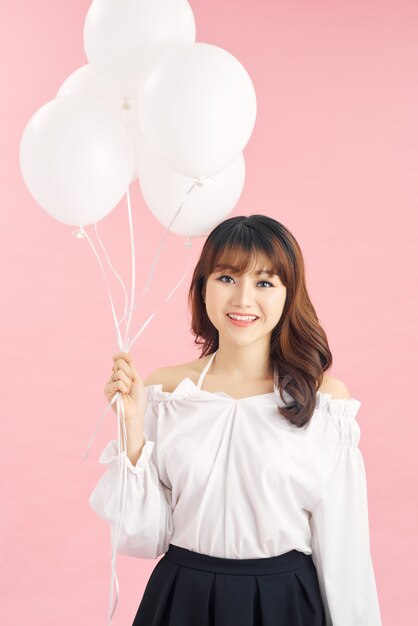 Beauty girl with white air balloons laughing, isolated on pink background