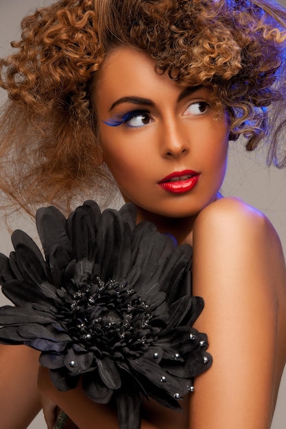 beauty and glamour concept - woman with long curly hair and big black flower