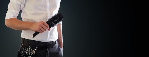 Photo beauty and hair salon, hairstyle and people concept - close up of male stylist with brush at salon over blank black background