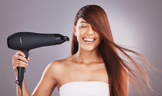 Beauty hairdryer and woman salon smile happy and excited isolated against studio gray background Hairstyle model and natural hair female with self care haircare and drying or styling