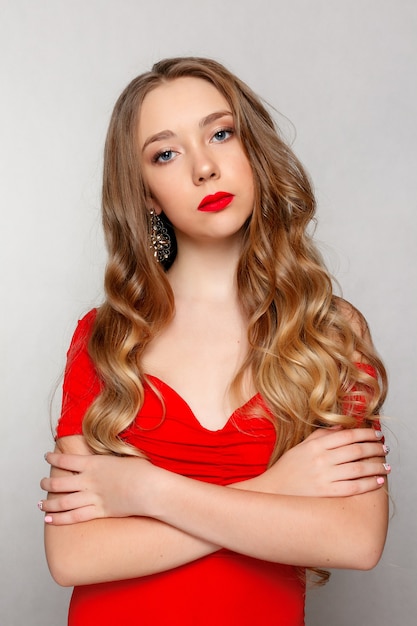 Beauty, hairstyle and people concept - Beautiful model brunette with long curled hair . Girl big necklace beads and chain . Jewelry and accessories .Hairstyle wavy curls. girl in red dress and jewelry