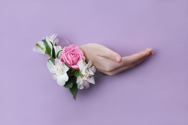 Beauty Hand with flowers in a hole in a purple paper