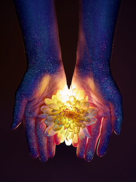 Photo beauty hands of a woman in ultraviolet light with flowers in the palms. cosmetics for hand skin care