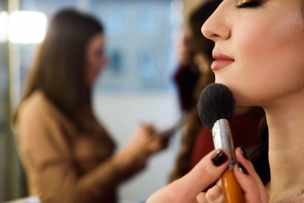 Beauty and health clean Skin of young female Model. Woman applying Powder Foundation with Brush