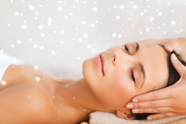 beauty, health, holidays, people and spa concept - beautiful woman in spa salon getting face or head massage