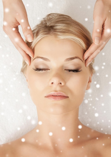 beauty, health, holidays, people and spa concept - beautiful woman in spa salon getting face or head massage