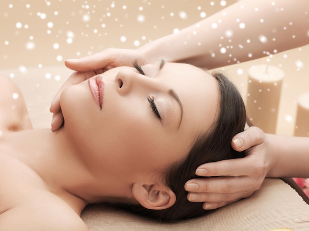 beauty, health, holidays, people and spa concept - beautiful woman in spa salon getting face or head massage