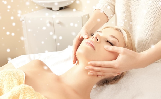 beauty, health, holidays, people and spa concept - beautiful woman in spa salon getting face or head massage