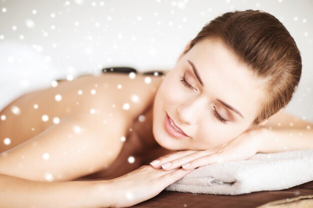 beauty, health, people and spa concept - beautiful young woman in spa salon lying on the massage desk