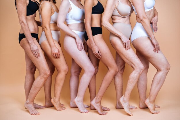 Beauty image of a group of women with different age, skin and body posing in studio for a body positive photoshooting. Mixed female models in lingerie on colored backgrounds