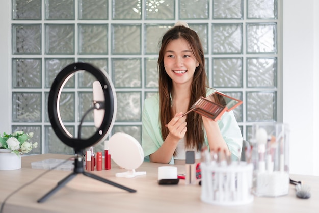 Beauty influencer concept Young woman apply eyeshadow to present product and record video for Vlog