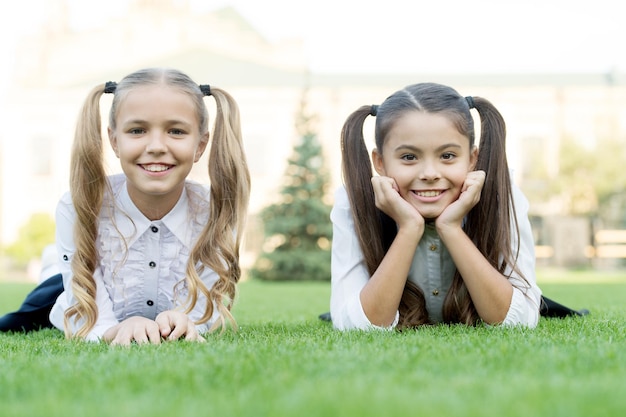 Beauty is whatever gives joy. Happy kids relax on green grass. Beauty look of little girls. Childs skincare products. Beauty salon. Beauty cosmetics. Summer vacation. School holidays. Feel beautiful.