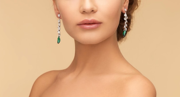 beauty and jewelry concept - beautiful woman in diamond and emerald earrings