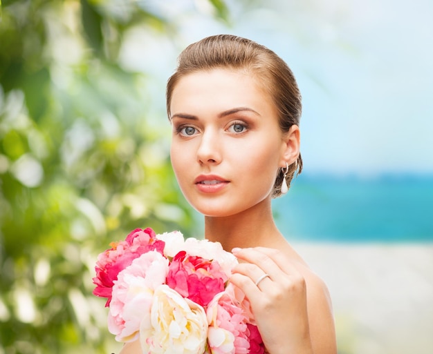 아름다움과 보석 개념 - 귀걸이, 반지, 꽃을 들고 있는 여성