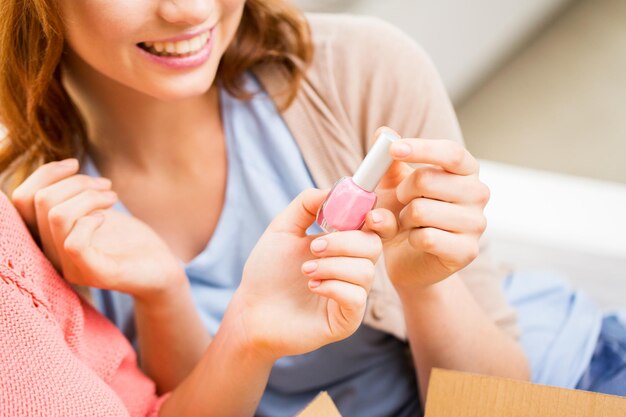 beauty, make up, cosmetics and people concept - close up of smiling young woman with pink nail polish