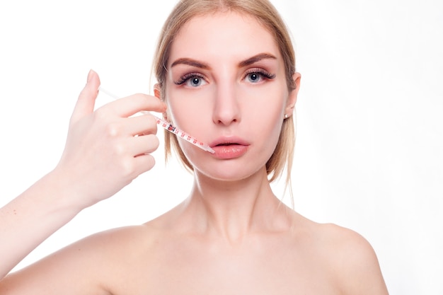 Beauty, make up and people concept - Attractive young woman gets cosmetic injection, isolated over white background. Doctors hands making an injection in face. Beauty Treatment.