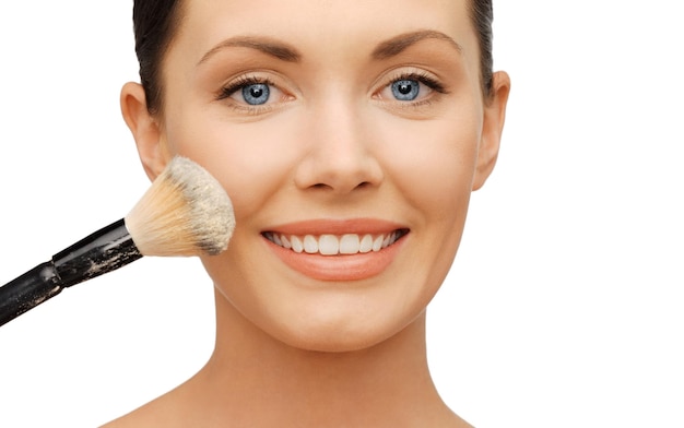 beauty and makeup concept - woman applying powder foundation with brush