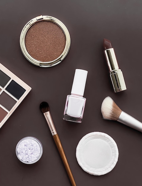 Beauty makeup and cosmetics flatlay design with copyspace cosmetic products and makeup tools on brown background girly and feminine style