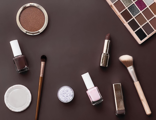 Beauty makeup and cosmetics flatlay design with copyspace cosmetic products and makeup tools on brown background girly and feminine style