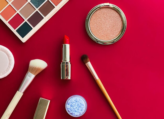 Beauty makeup and cosmetics flatlay design with copyspace cosmetic products and makeup tools on red background girly and feminine style concept