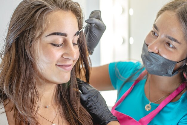 Beauty master brow painter paints eyebrows by coloring them with henna