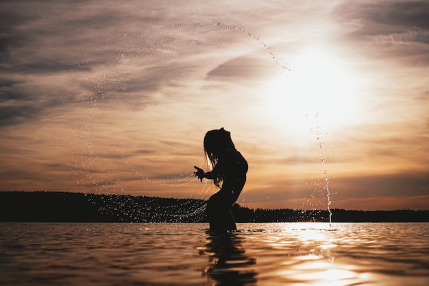 Ragazza di modello di bellezza che spruzza acqua con i suoi capelli