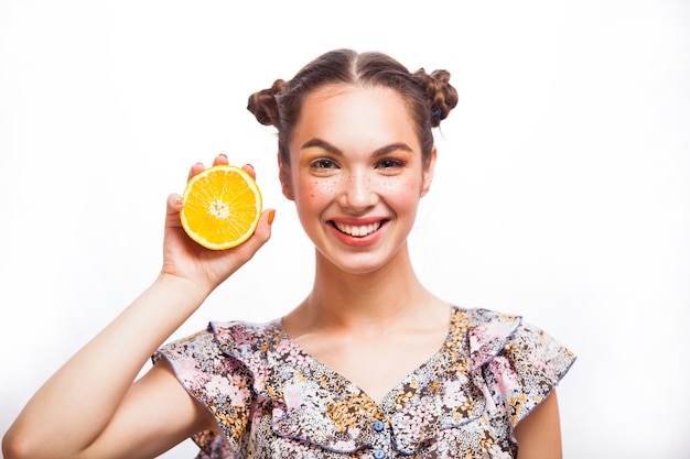 Beauty Model Girl with Juicy Oranges. Beautiful Joyful teen girl with freckles, funny red hairstyle and yellow makeup . Professional make up. Orange Slices. Isolated on a white background