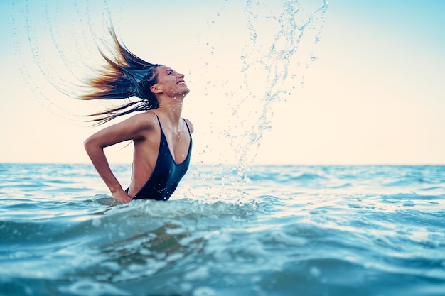 Beauty model woman splashing water with her hair a young woman