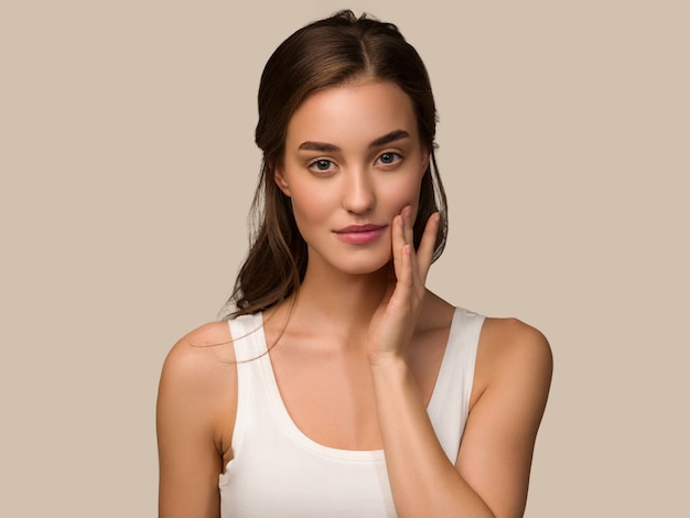 Beauty model woman with healthy natural make up clean skin  touching her face Color background brown