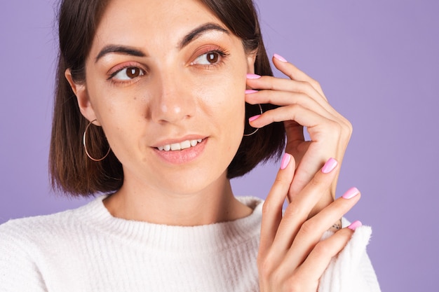 Beauty nail concept, petty woman with pink spring color manicure white sweater purple wall