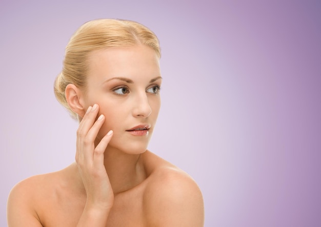 Beauty, people and health concept - beautiful young woman face over violet background