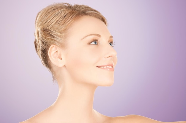 beauty, people and health concept - beautiful young woman face over violet background