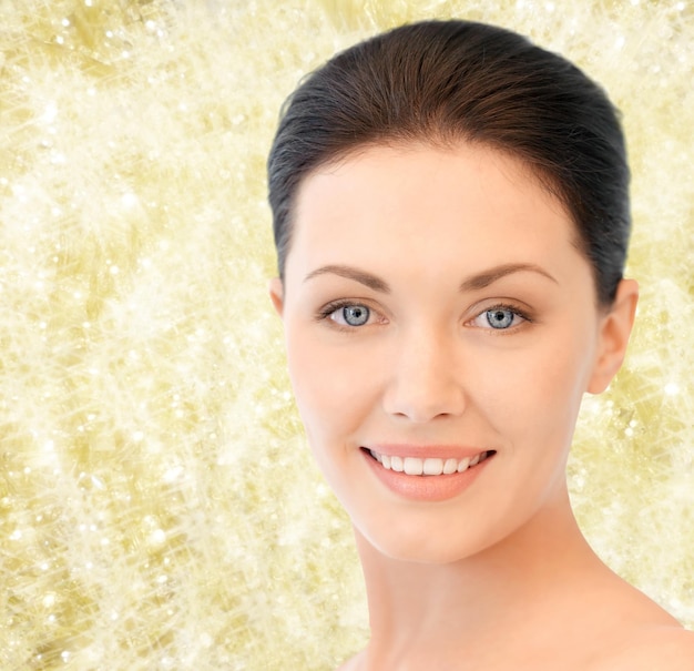 beauty, people and health concept - beautiful young woman face over yellow lights background