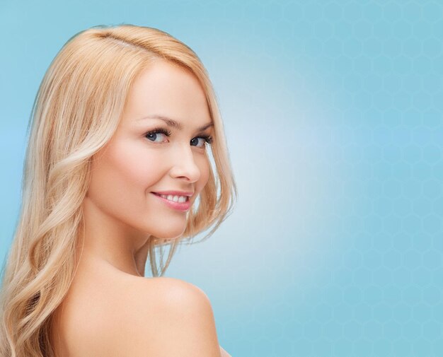 beauty, people and health concept - beautiful young woman with bare shoulders over blue background