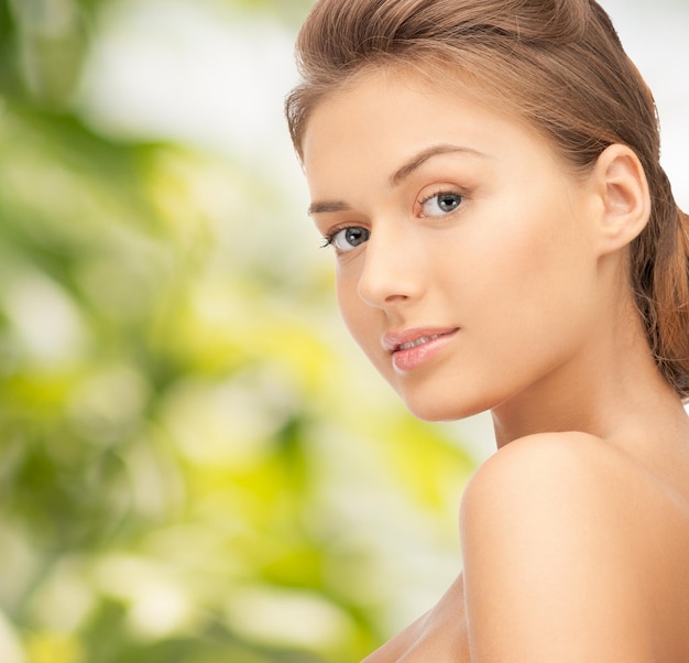 beauty, people and health concept - beautiful young woman with bare shoulders over green background