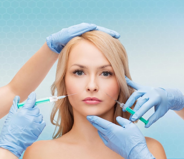 beauty, people and plastic surgery concept - woman face and beautician hands with syringes