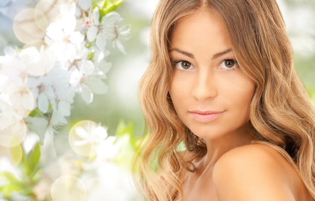 Foto bellezza, persone, estate, primavera e concetto di salute - bella giovane donna faccia su sfondo verde giardino fiorito