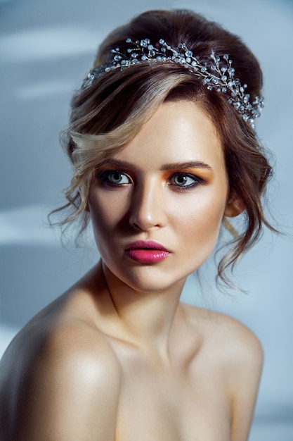 Beauty portrait of beautiful fashion model with makeup, and collected hairstyle. studio shot on blue background.