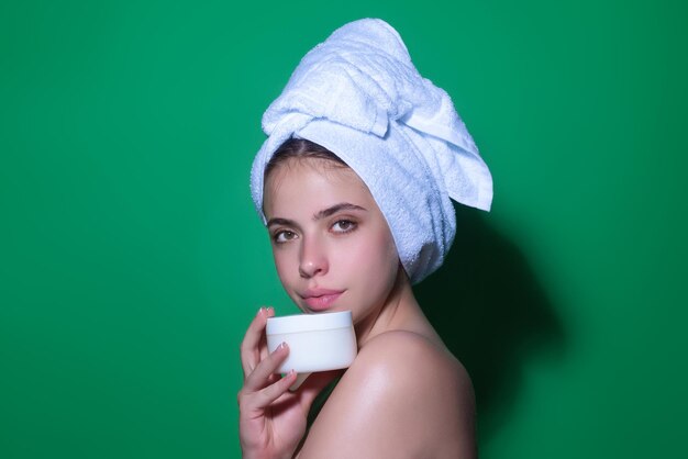 Photo beauty portrait of a beautiful half naked woman applying face cream isolated on studio background