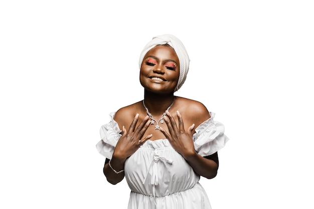 Beauty portrait of black muslim woman weared white dress and headscarf on white background. Softness and wellness of body and skin.